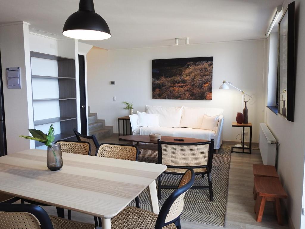 una sala de estar con un sofá, una mesa y sillas en Departamentos Natales, en Puerto Natales