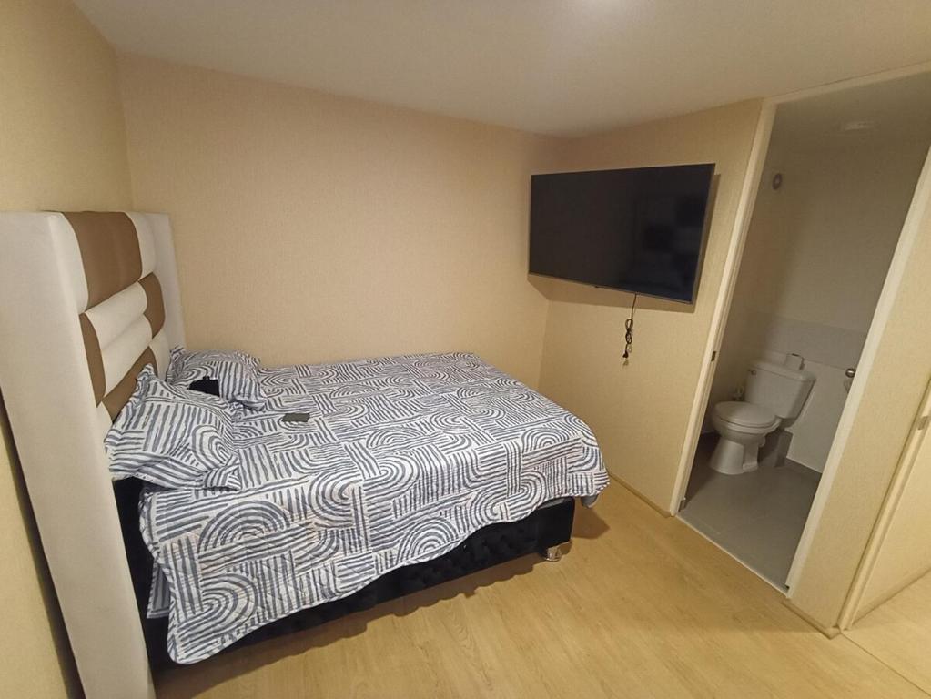 a hotel room with a bed and a flat screen tv at Departamento en estreno condominio la media central in Lima