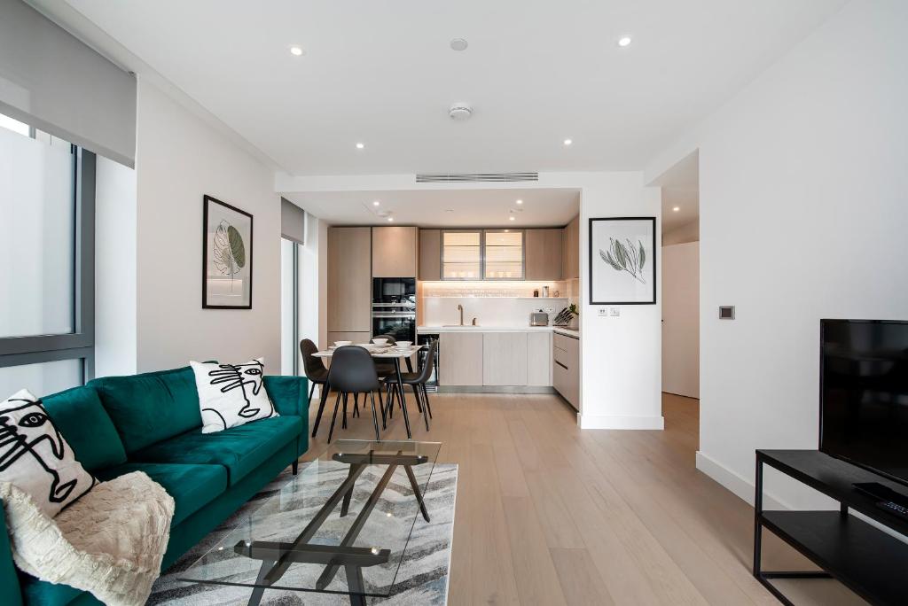 Hotel Battersea Power station 2 Bed Close To Harrods, a living room with a green couch and a kitchen at Battersea Power station 2 Bed Close To Harrods in London