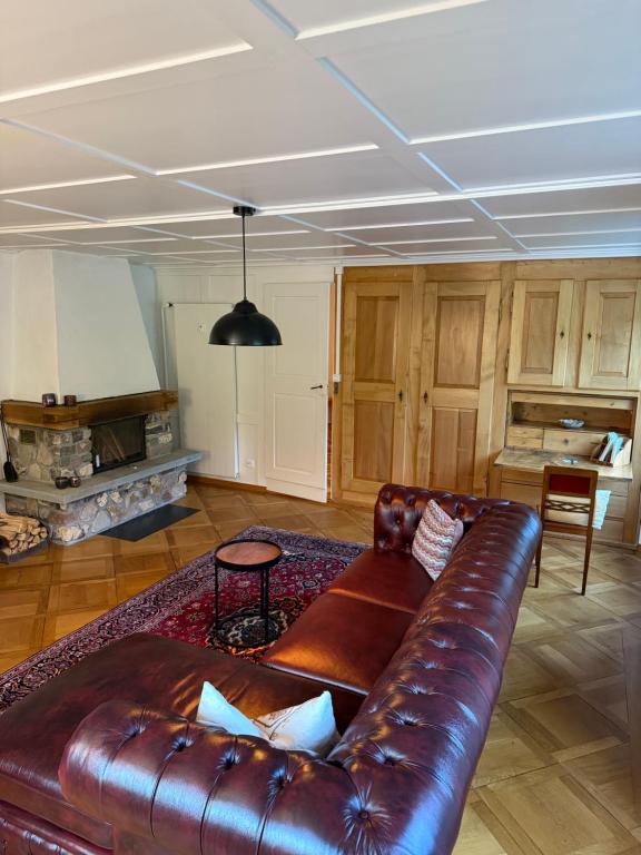 un sofá de cuero en una sala de estar con chimenea en Schweizerhaus Glarus - Historisch & Stilvoll mit Garten, en Ennenda
