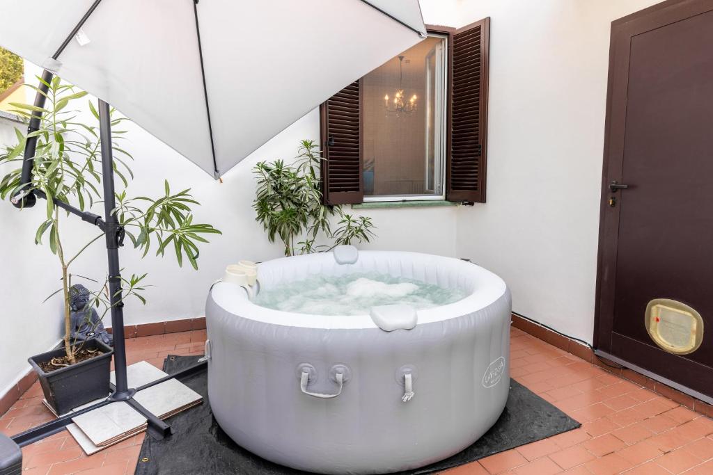 a bath tub in a room with an umbrella at Zen Retreat with Jacuzzi, Patio & Private Garage Plus Automatic Check in 24 7 with Netflix Dazn and Disney Plus in Casale Monferrato