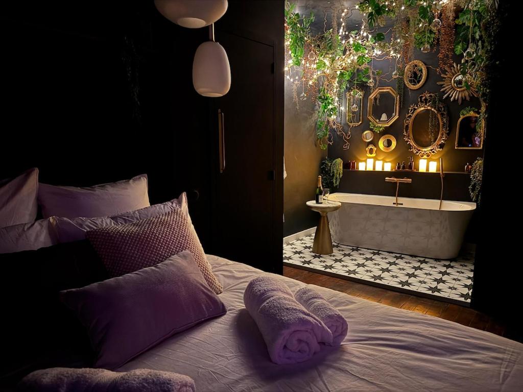 a bedroom with a tub and a bed with purple pillows at Suite Romantique, hyper centre in Caen