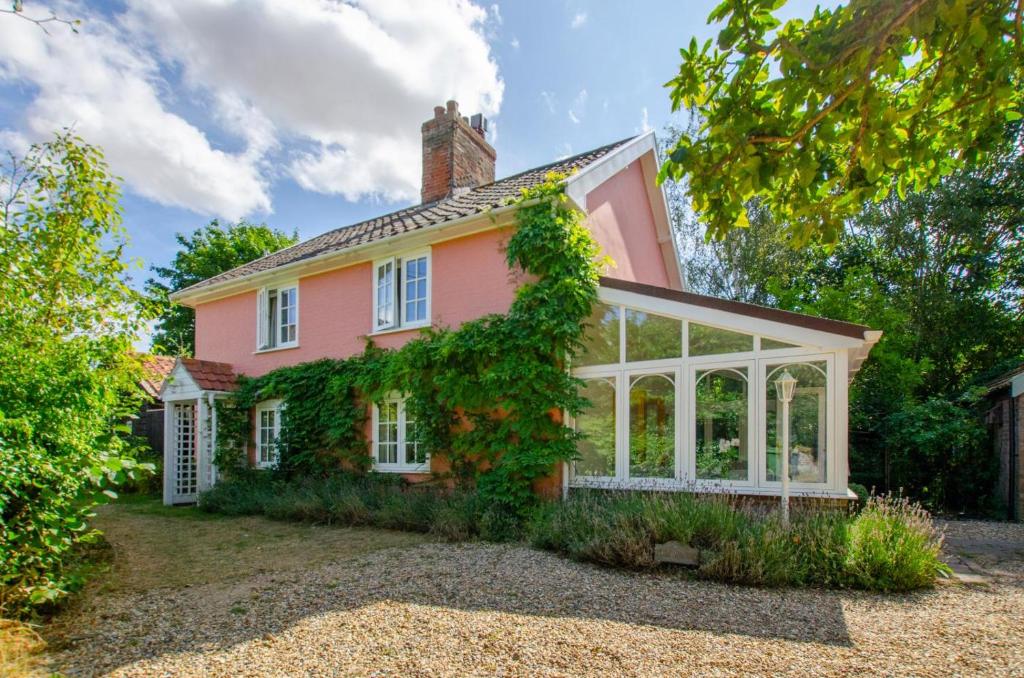 an exterior view of a pink house with a conservatory at Barn Meadow Cottage in Yoxford