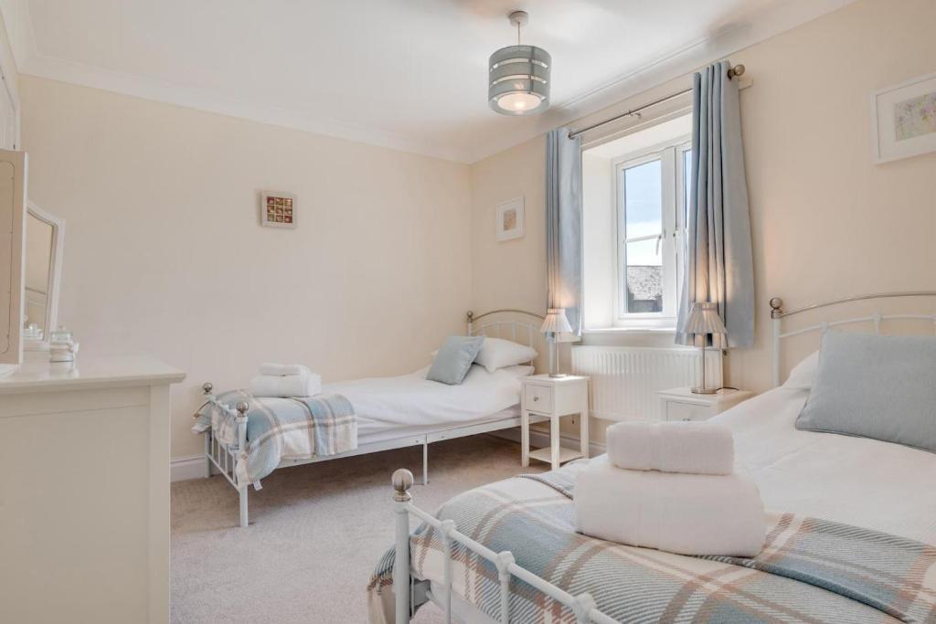 a bedroom with two beds and a window at Church Meadow Cottage in Trimingham