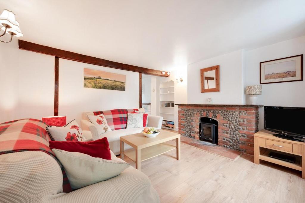 a living room with a couch and a fireplace at Poppy Cottage in Briston