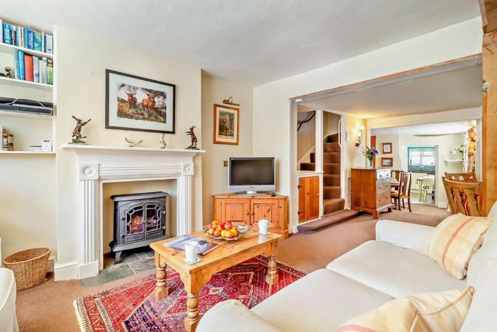 a living room with a fireplace and a television at Coach House Cottage in Wickham Market