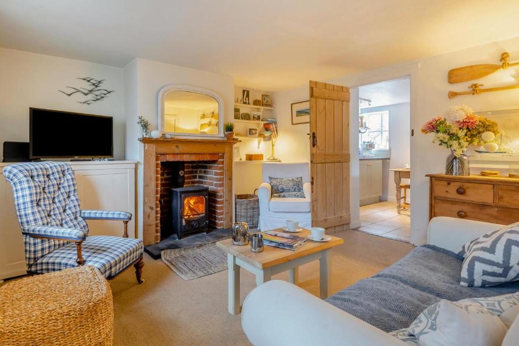 a living room with a couch and a fireplace at Stone Cottages - Bodham in Bodham