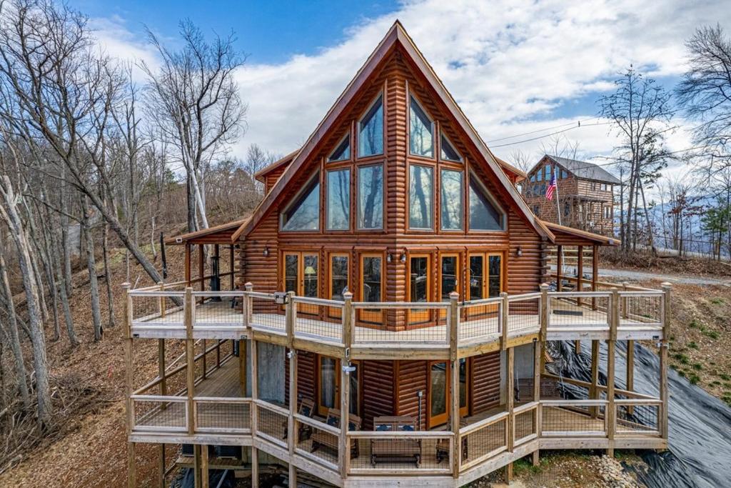 a log cabin with a large deck in the woods at Climbing to New Heights cabin in Cartertown