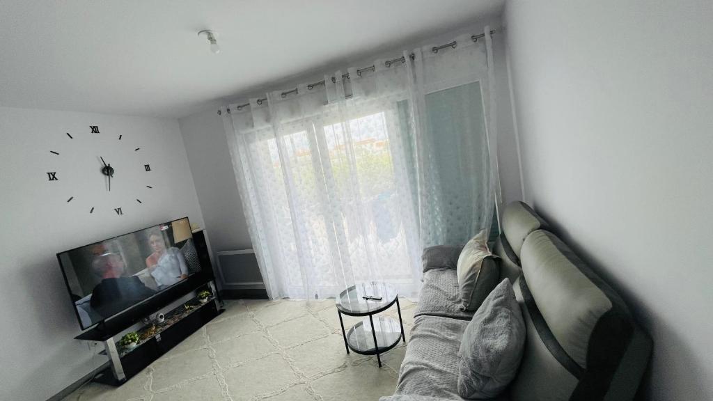 ein Wohnzimmer mit einer Couch und einer Uhr an der Wand in der Unterkunft Chonanson in Perpignan