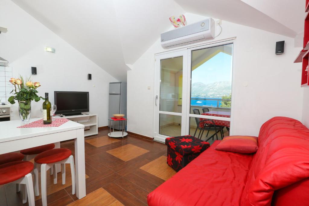 uma sala de estar com um sofá vermelho e uma mesa em Sunrise Apartments em Cavtat