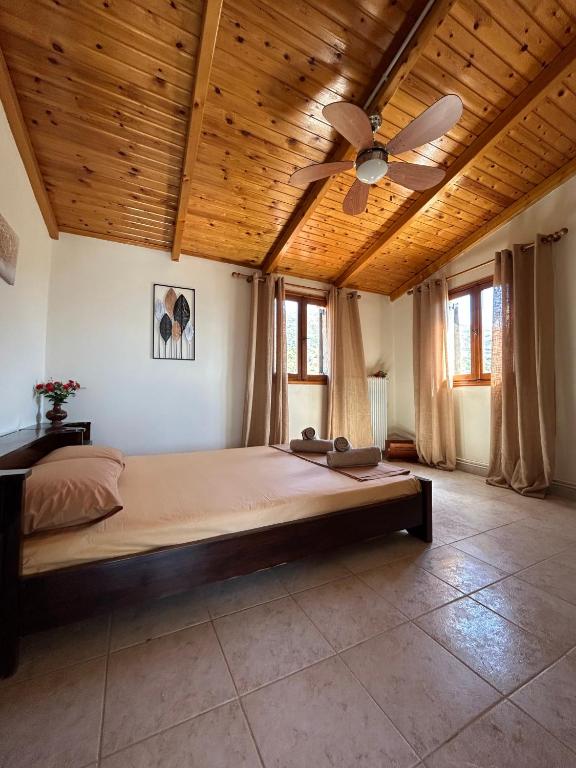 a bedroom with a large bed with a ceiling fan at Ziras Traditional Villa in Áno Váthia