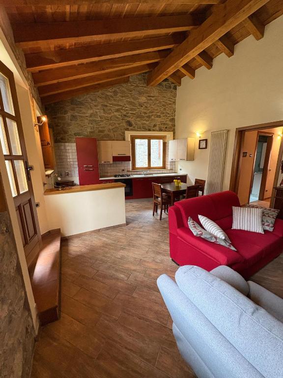 a living room with a red couch and a kitchen at La Casa di Bianca - Intero appartamento in Collagna