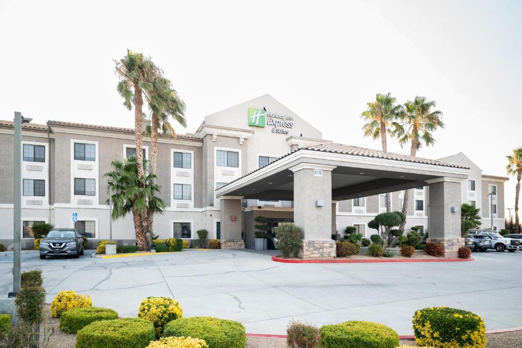 a hotel building with a parking lot and palm trees at Holiday Inn Express Hotel & Suites Hesperia by IHG in Hesperia