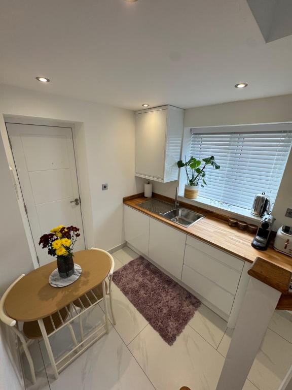 a small kitchen with a table and a sink at Siennas Modern 1 bed room apartment with ensuite in Kidlington
