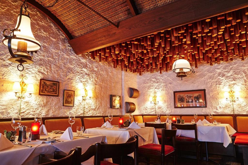 a dining room with white tables and chairs and a wall at Steigenberger Graf Zeppelin in Stuttgart
