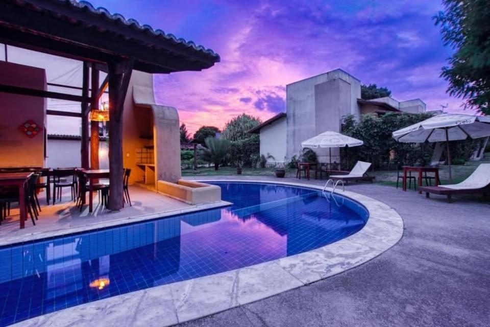 a swimming pool in a backyard with tables and umbrellas at Oka Káa - Bosque da Praia Pipa Flat 33 in Pipa