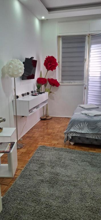 Habitación con cama y mesa con flores rojas en AIK Kula studio, en Jagodina