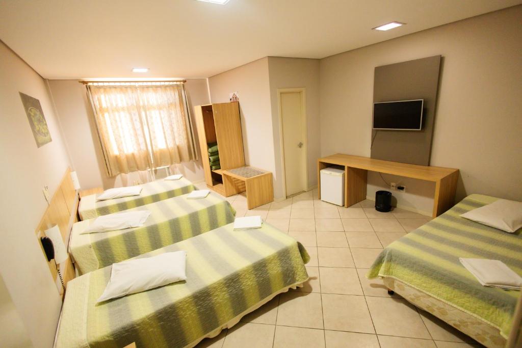 a hotel room with two beds and a desk at CHA Mime Hotel in Blumenau