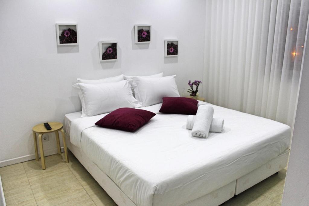 a white bed with red pillows in a room at Nine Senses in Furadouro