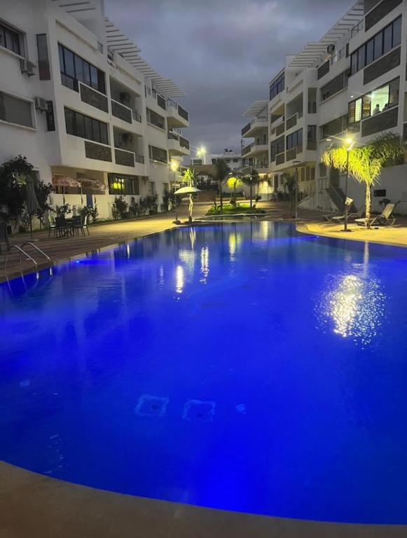 a large blue swimming pool in front of a building at Résidence oasis beach mansouriah in Mohammedia