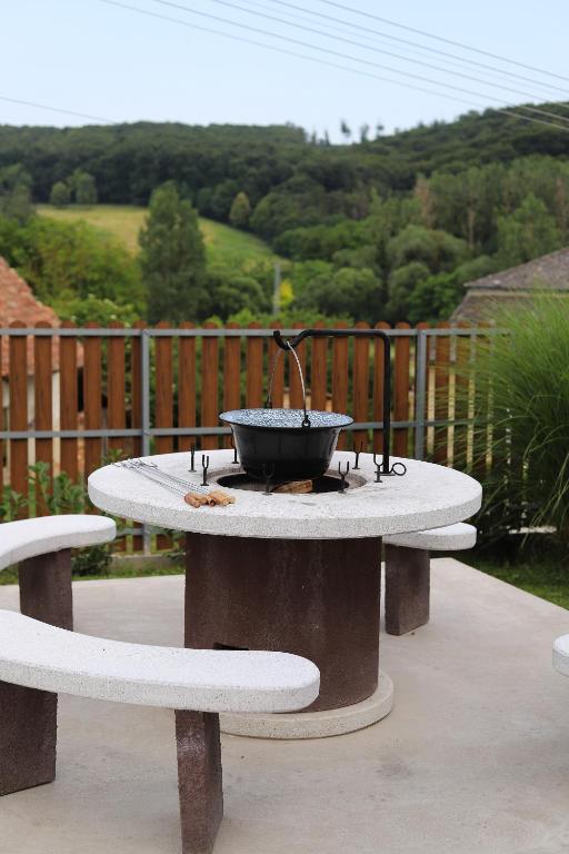 a fire pit on a table with two benches at Panoráma Vendégház Jásd in Jásd