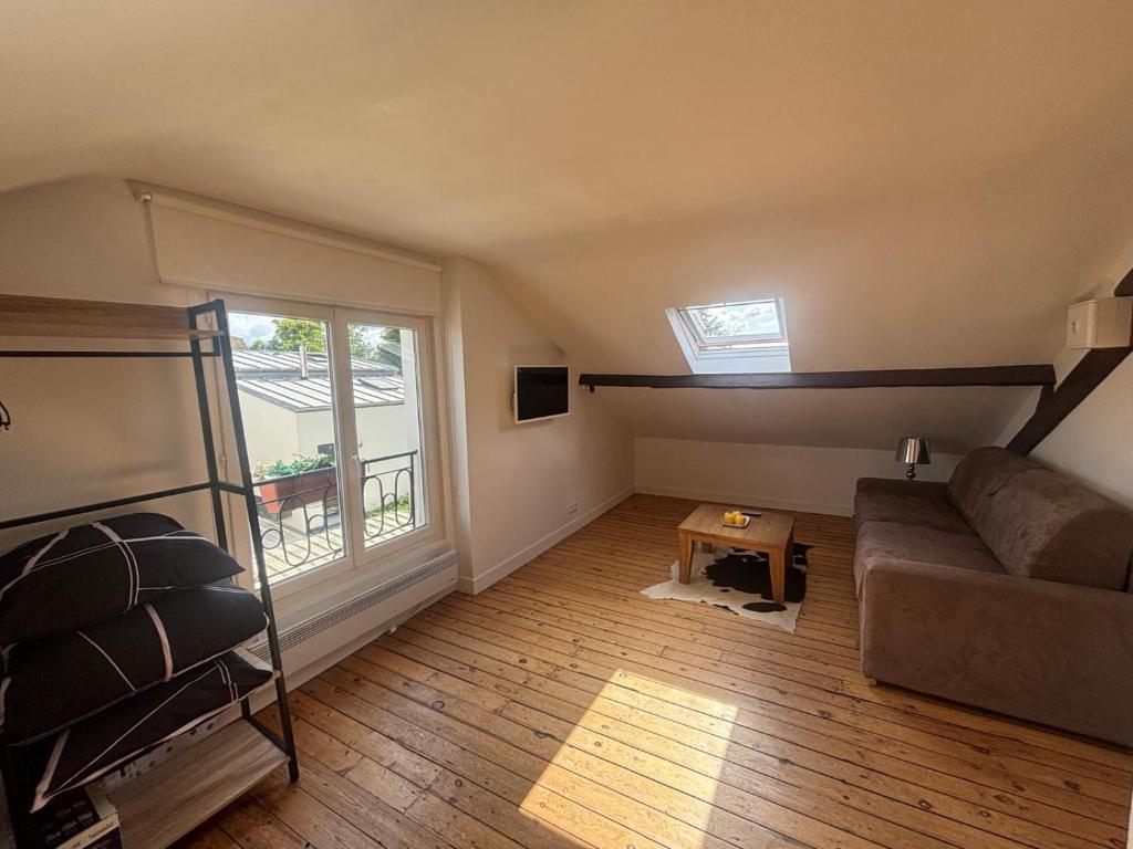 a living room with a couch and a window at Logement atypique in Asnières-sur-Seine