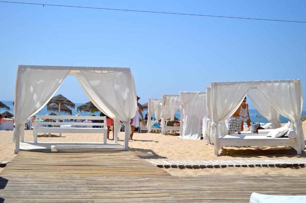 - une rangée de lits sur une plage avec une promenade dans l'établissement Apartment Qiu, à Costa da Caparica