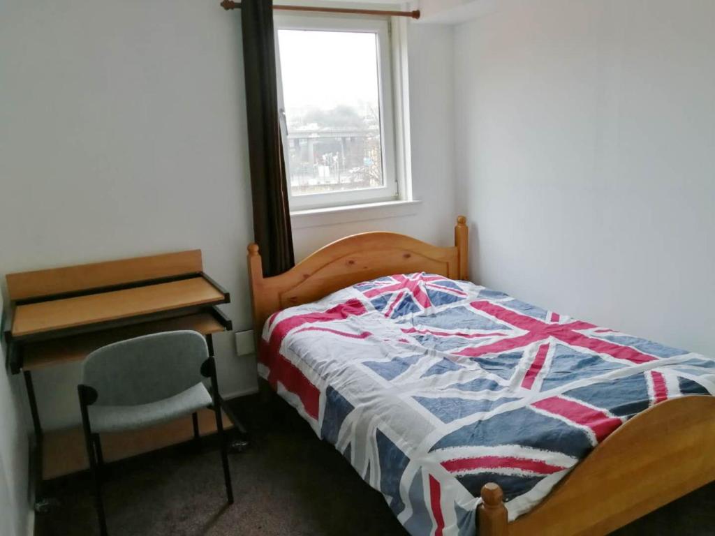 a bedroom with a bed and a desk and a window at City Centre Room in Glasgow