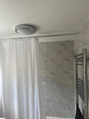 a shower with a white shower curtain and a shower at 65 Penn Crescent, Hayward Heath, Mid Sussex RH16 3HP in Moffat