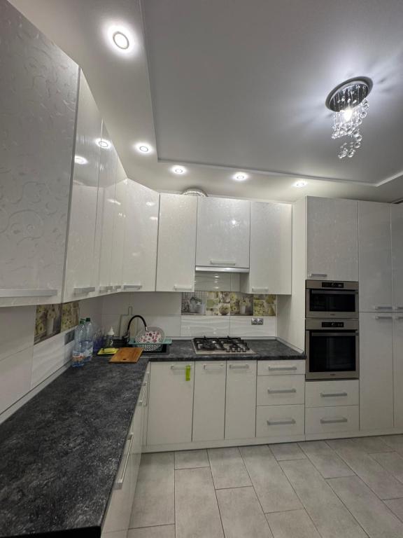a kitchen with white cabinets and a black counter top at Апартаменти новобудова Львів in Lviv