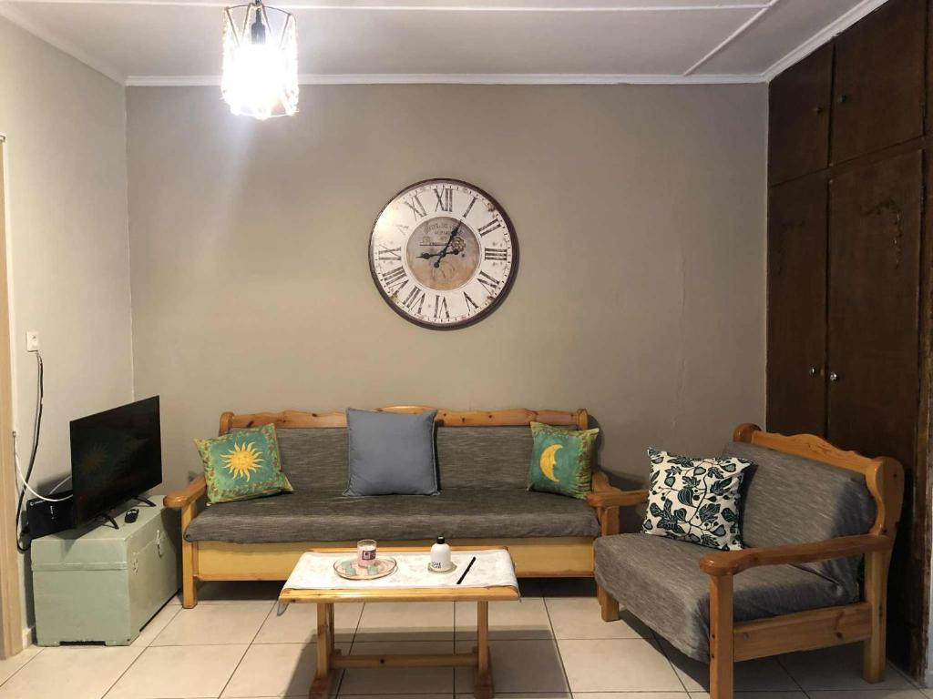 een woonkamer met een bank en een klok aan de muur bij Kallimasia Chios - Iraklis House in Kallimasiá