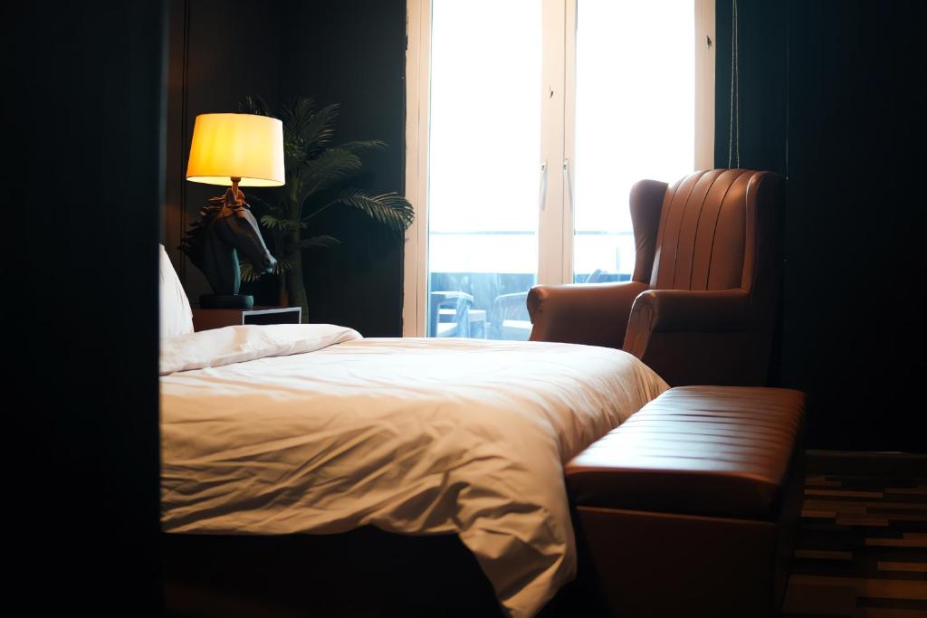 Un dormitorio con una cama, una silla y una ventana en Gold Crest Mall Luxury Apartments with Balcony by NestNow in DHA Phase 4 Lahore, en Lahore