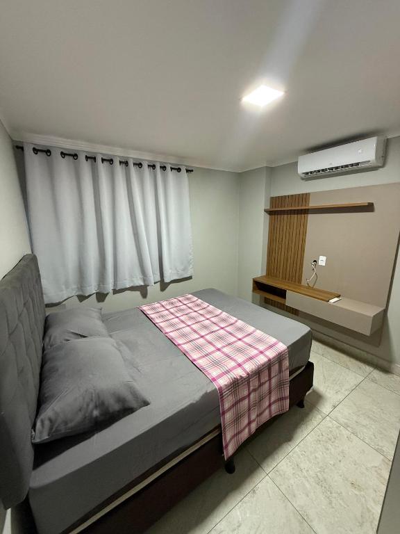 een slaapkamer met een bed met een geruite deken erop bij Confort Flat Campina Grande in Campina Grande