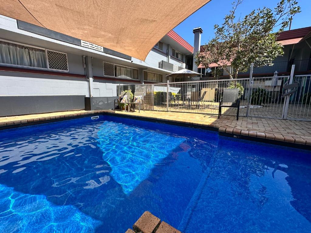 a large blue swimming pool in front of a building at Airway Motel in Brisbane
