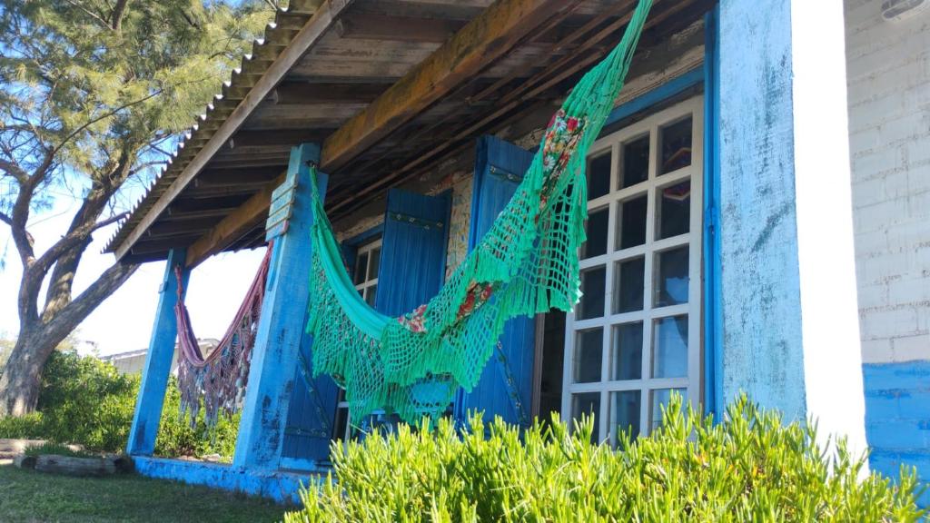 ein blaues Haus mit einer Hängematte auf der Veranda in der Unterkunft Casa beiramar, vista mar e pinheiros, pé na areia in Xangri-lá