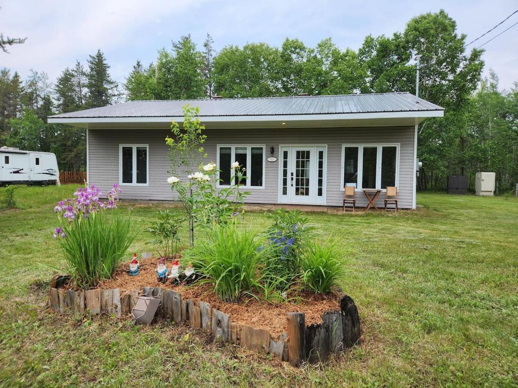 une petite maison avec un jardin en face de celle-ci dans l'établissement Chalet au lac Saint-Jean, à Dolbeau-Mistassini