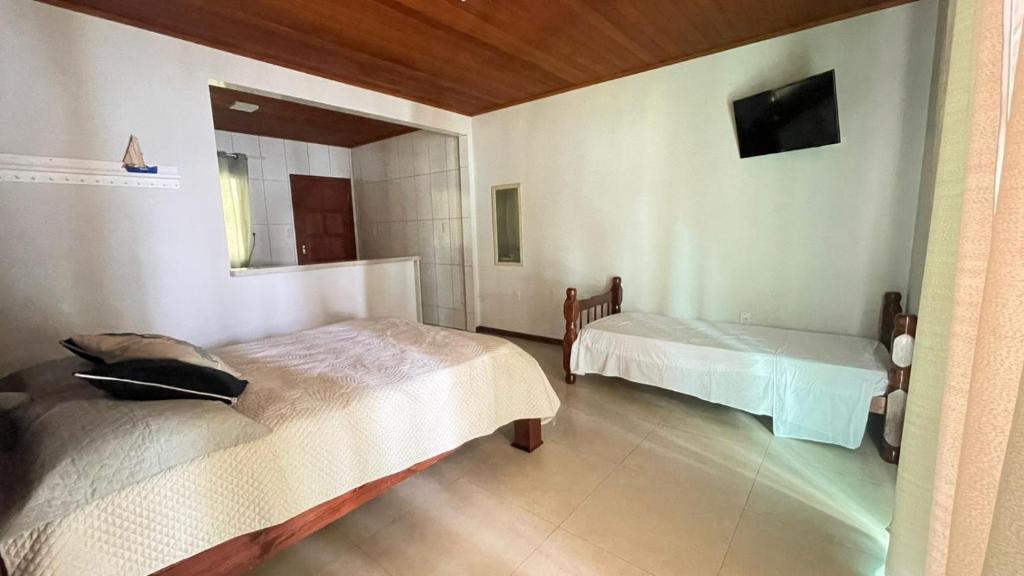 a bedroom with two beds and a tv on the wall at Carneiro's House in Praia de Araçatiba