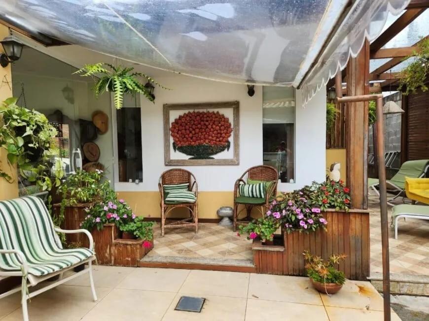 a patio with chairs and flowers in a room at Casa das Hortênsias in Teresópolis