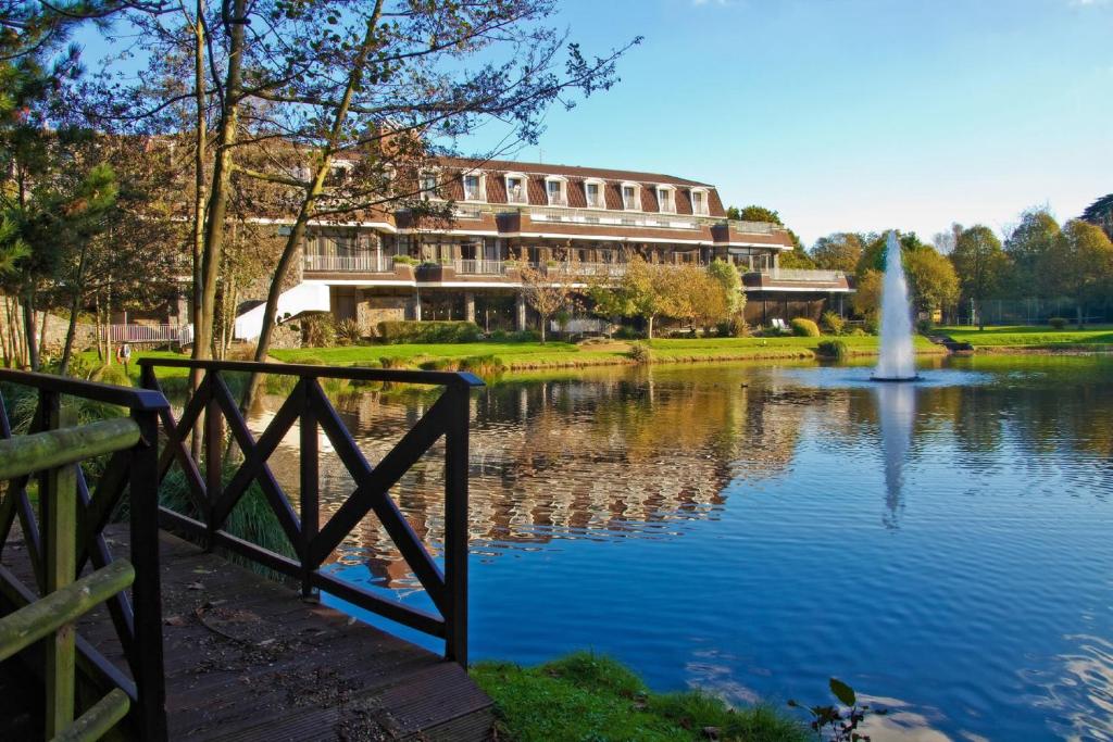 a building next to a pond with a fountain at St. Pierre Park Hotel & Golf in St. Peter Port