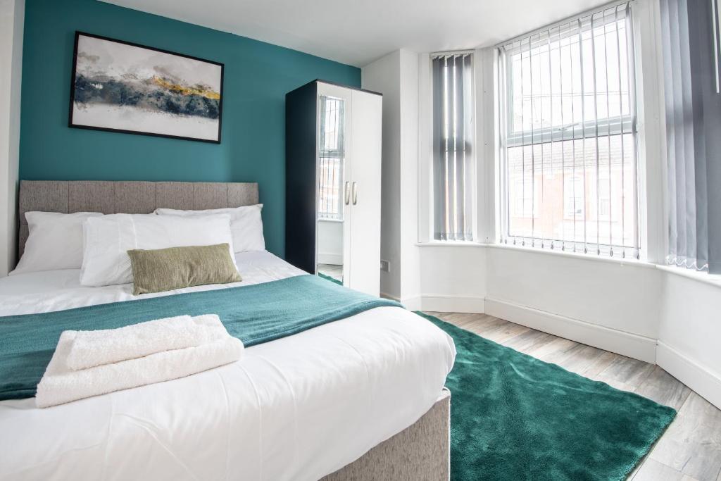a bedroom with blue walls and a bed with a green rug at Hiltop 2Bed Apartment, Near City Centre, Sleeps 4 with Parking in Coventry