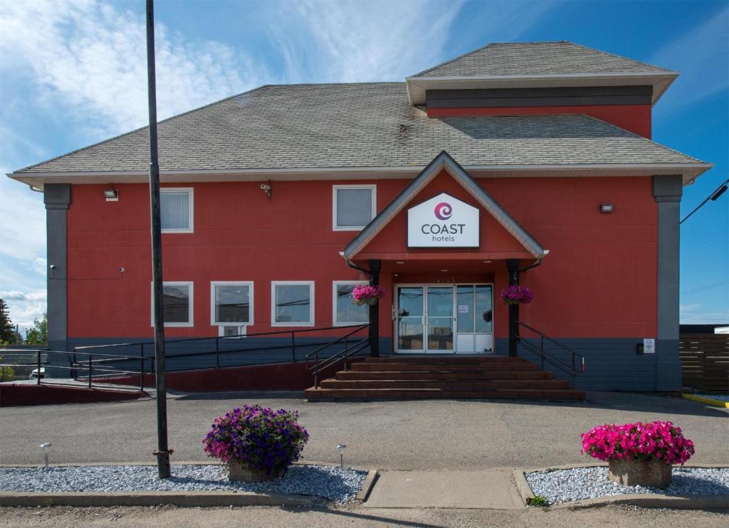 ein rotes Bürogebäude mit einem Schild darauf in der Unterkunft Coast Fort St John Hotel in Fort Saint John