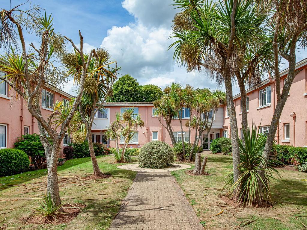a pink building with palm trees in front of it at Garden Apartment - Uk44654 in Paignton