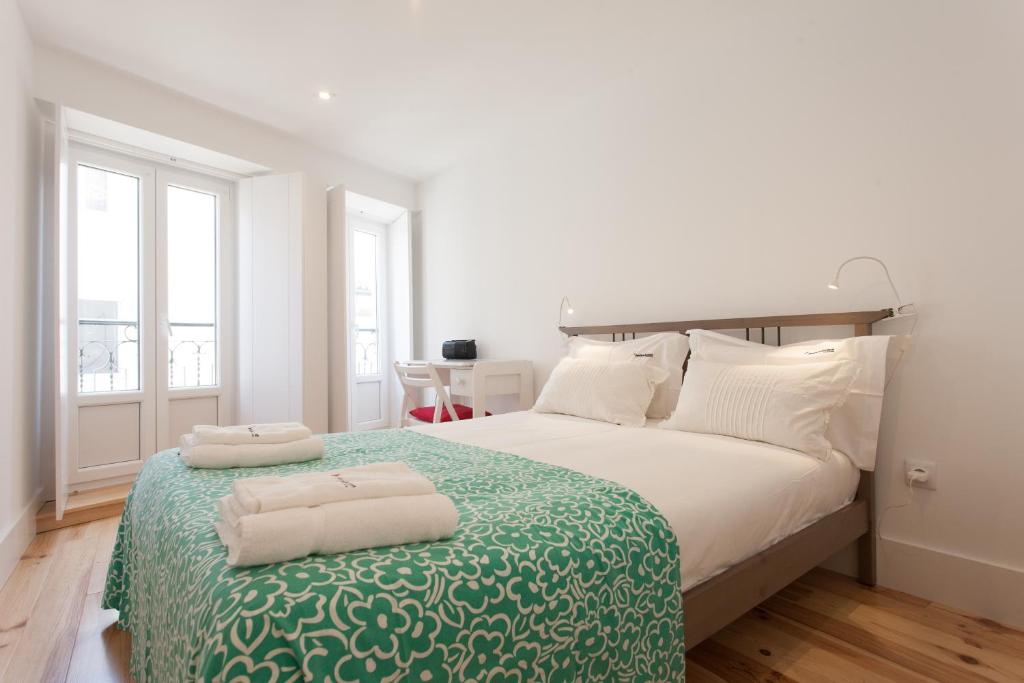 リスボンにあるFLH Alfama Bright Apartmentの白いベッドルーム(大型ベッド1台、タオル2枚付)