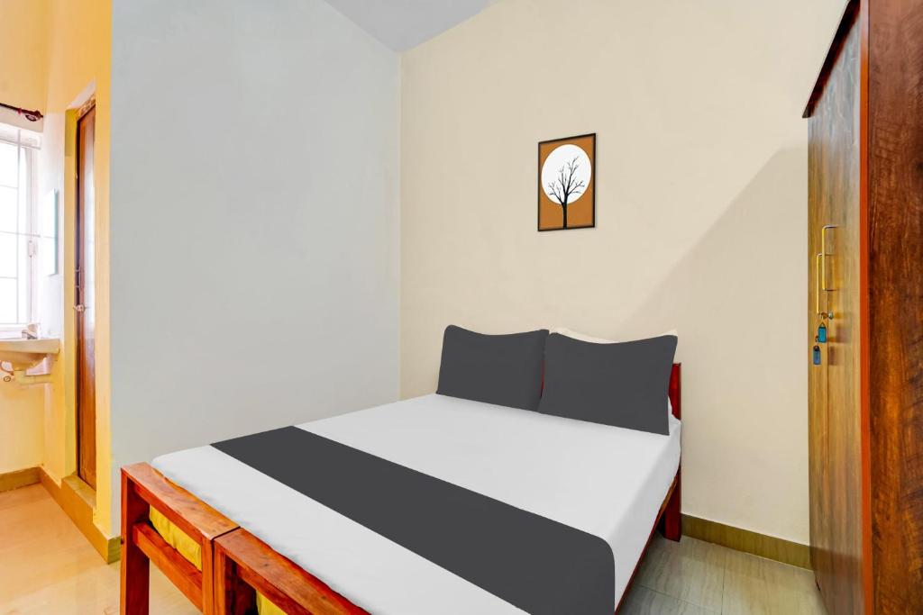 a bedroom with a white bed with a clock on the wall at Super Hotel O Okkilipalayam in Coimbatore