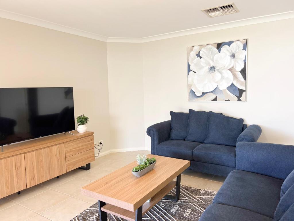 ein Wohnzimmer mit einem blauen Sofa und einem Fernseher in der Unterkunft Yarrawah Crescent in Lake Albert
