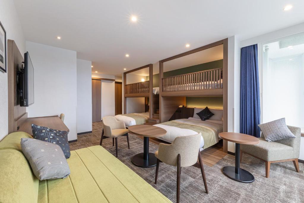 a hotel room with two beds and a couch at HOTEL MYSTAYS Hakodate Station in Hakodate