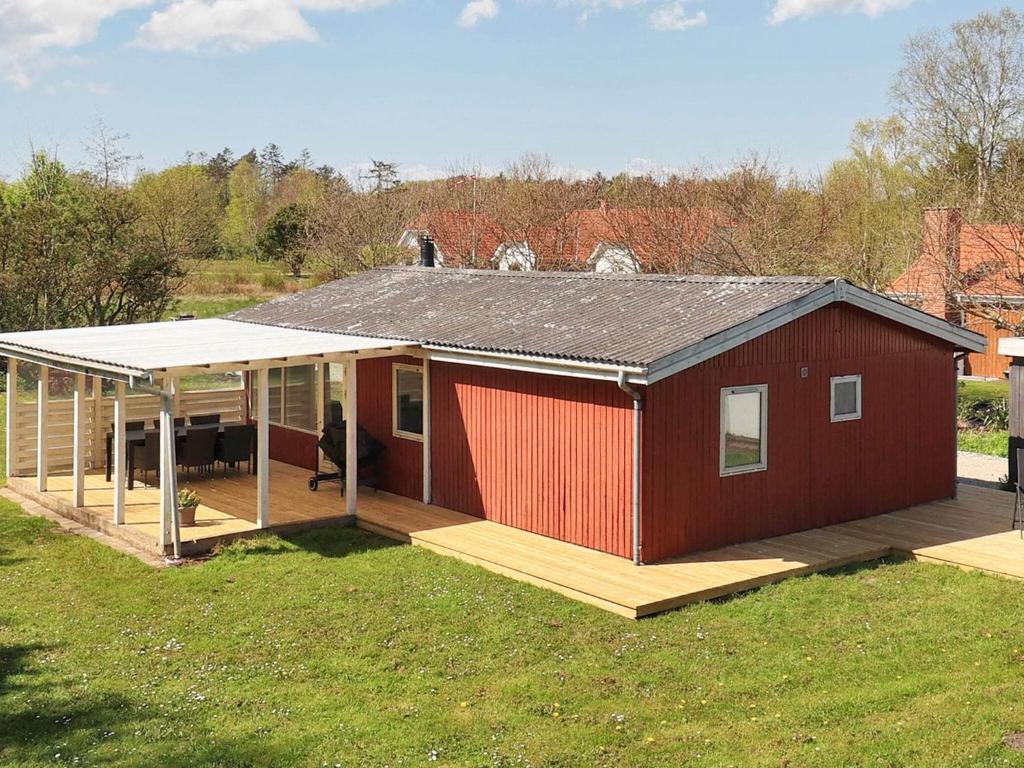 a red house with a porch on a grass field at 6 person holiday home in Hals-By Traum in Hals