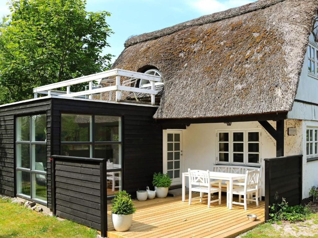 ein Anbau an ein Reetdachhaus mit Terrasse in der Unterkunft Tranquil Waterfront Cottage-By Traum in Hadsund