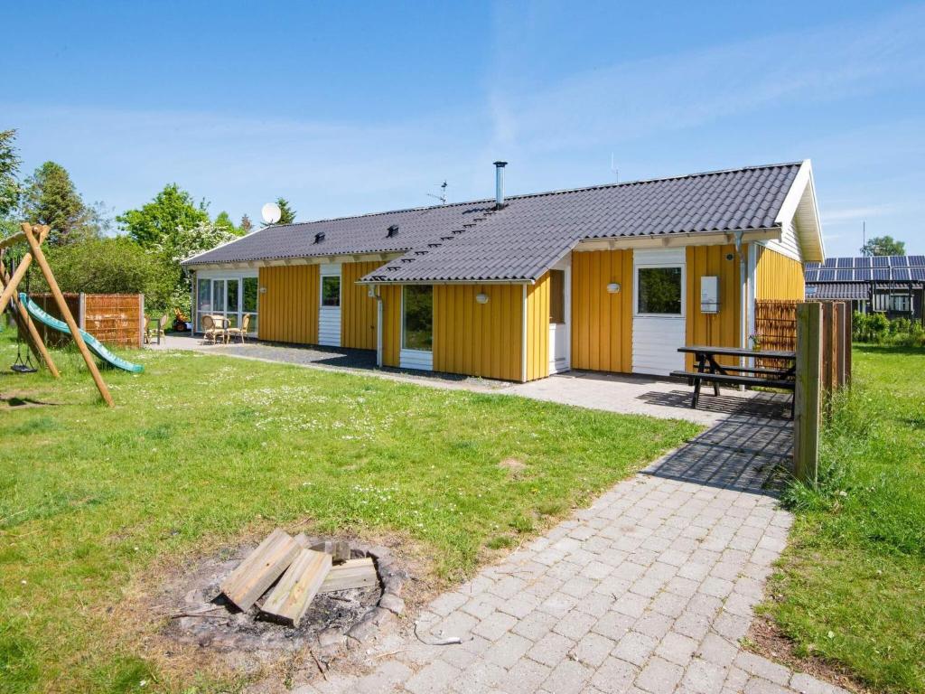 a yellow house with a picnic table in a yard at 10 person holiday home in Ørsted in Ørsted