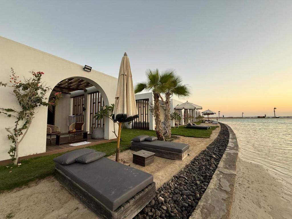 a house with an umbrella and beds next to the water at Le sidi Luxury Hotel Cabana Hacienda bay in El Alamein